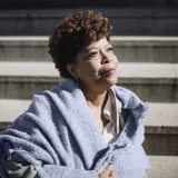 photo of older black woman in blue shawl gazing into the distance