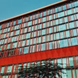 Colorful facade of JP Morgan building with red accents under blue sky.