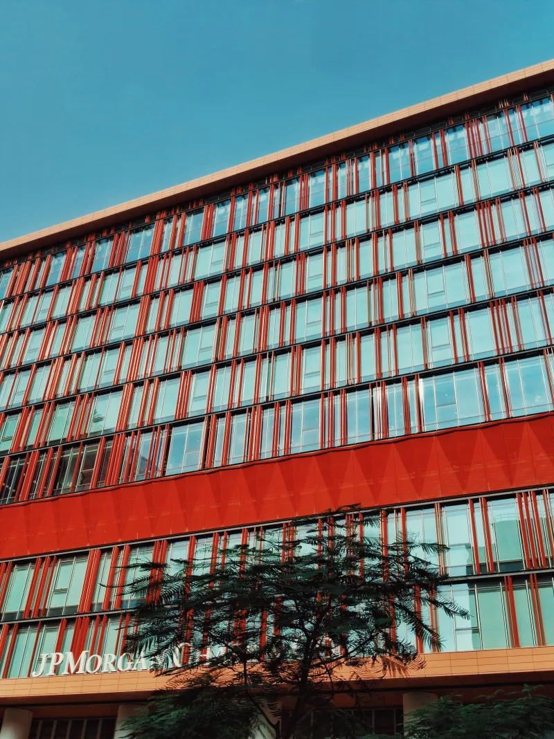 Colorful facade of JP Morgan building with red accents under blue sky.