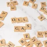 Scrabble tiles on marble spelling 'oil' and 'gas', concept for energy and creativity.