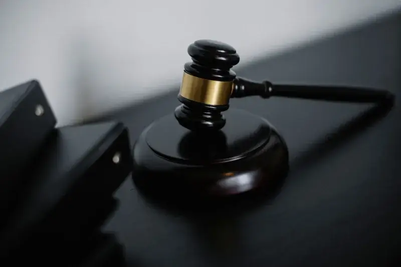 High angle of shiny wooden ceremonial mallet with golden detail placed on judge tale near documents folders