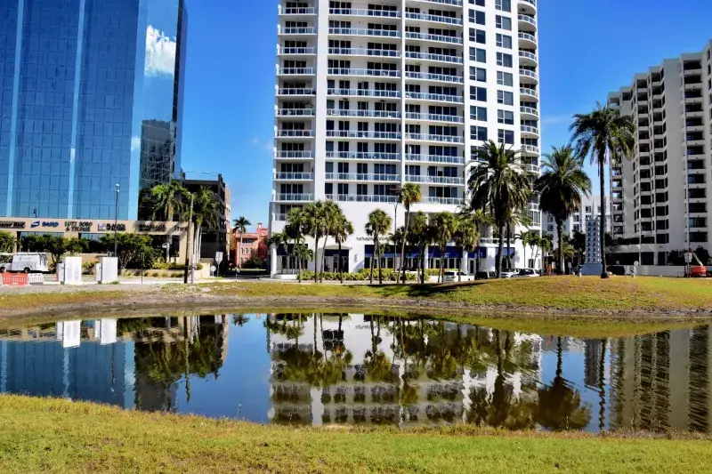 A vibrant urban scene in Sarasota, Florida, featuring buildings and a reflecting pond.