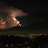 Lightning illuminates Caracas's night sky, capturing a striking cityscape under stormy clouds.
