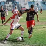 Competitive soccer match with players in action at an outdoor football field.