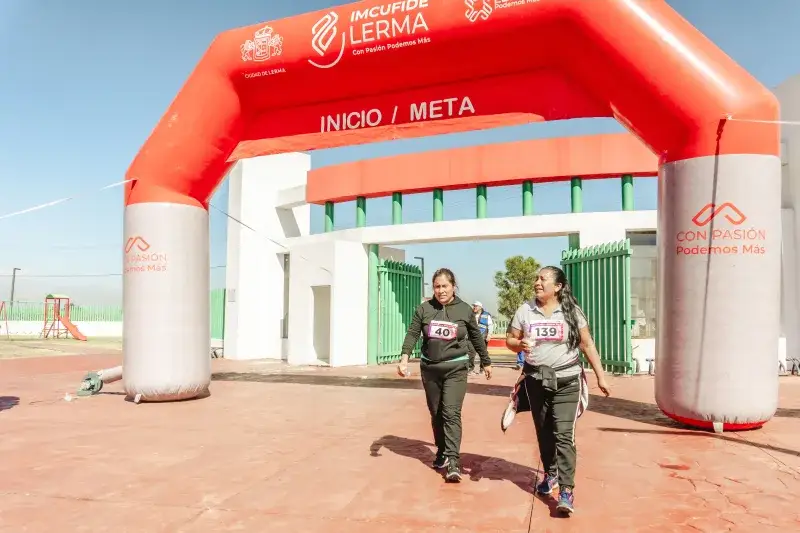 Two women cross finish line at marathon in Santa María Atarasquillo, Mexico.
