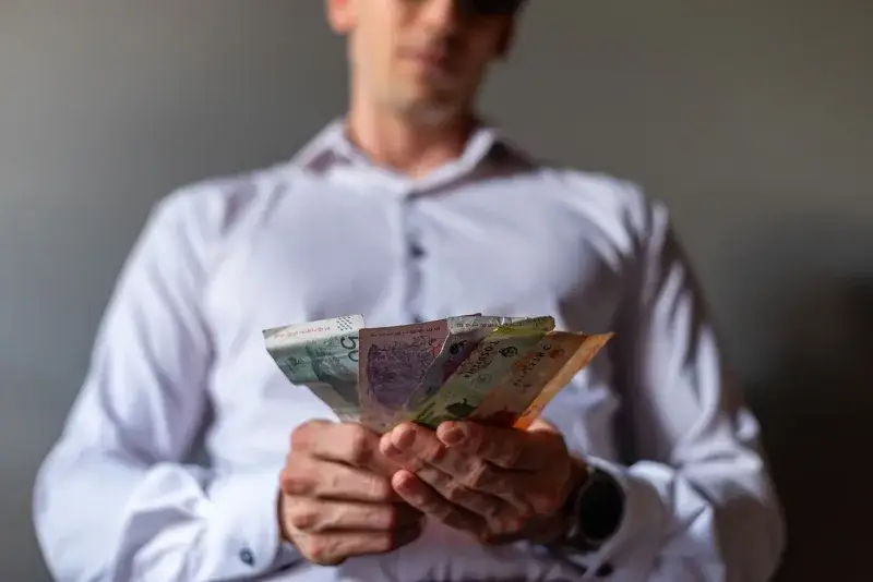 Man holding Argentine Peso banknotes in Buenos Aires, Argentina, illustrating currency concept.