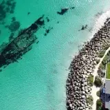 Drone shot of an underwater shipwreck near Perth, Australia with turquoise waters and rocky shoreline.