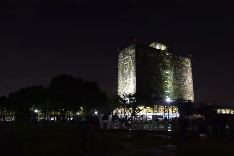 Illuminated facade of the UNAM Central Library at night in Mexico City, a UNESCO World Heritage Site.