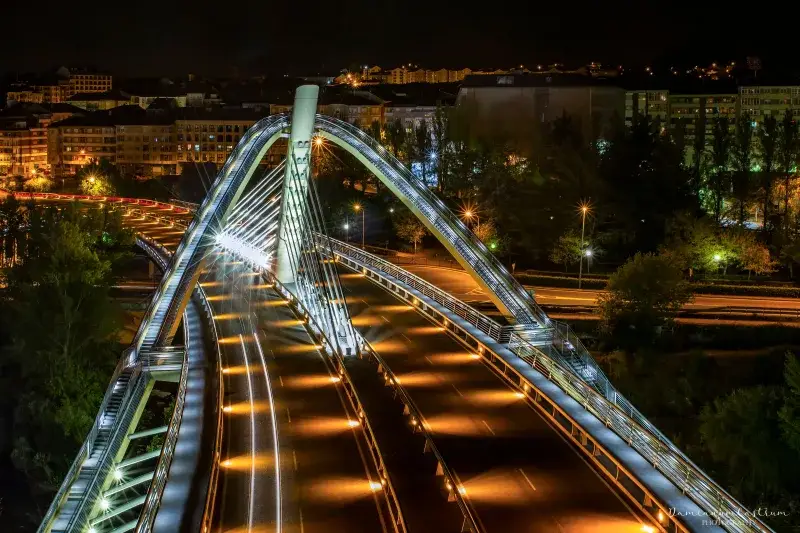 Majestic night view of the illuminated Ponte do Milenio bridge in Ourense, Spain, showcasing urban lights and architectural beauty.