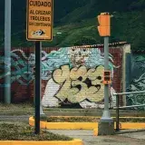 Street art mural and road signs reflecting cultural cityscape in Mérida, Venezuela.