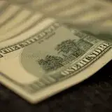 Detailed shot of multiple US hundred dollar bills fanned out on a flat surface, symbolizing wealth.