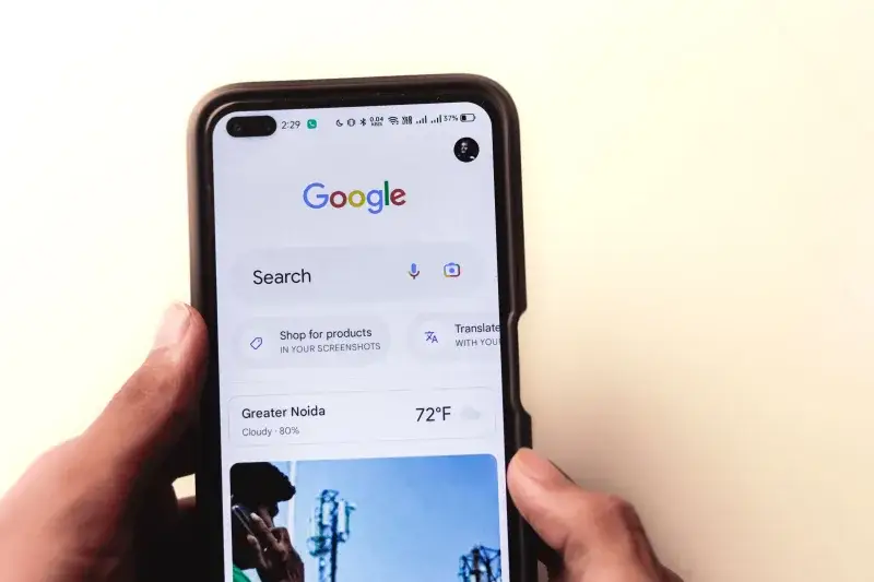 Un primer plano de una mano sosteniendo un smartphone con la búsqueda de Google mostrada en la pantalla.