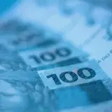 Blurred close-up view of Brazilian 100 real banknotes, showcasing currency details.