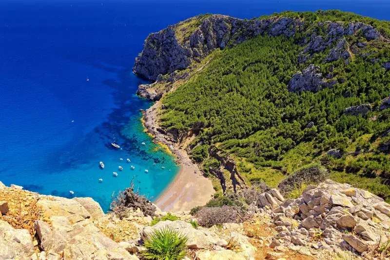 Stunning aerial view of Cala Figuera beach in Mallorca, Spain with turquoise waters and lush cliffs.
