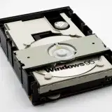Close-up of a retro CD-ROM drive with a Windows 95 disc, showcasing vintage technology.