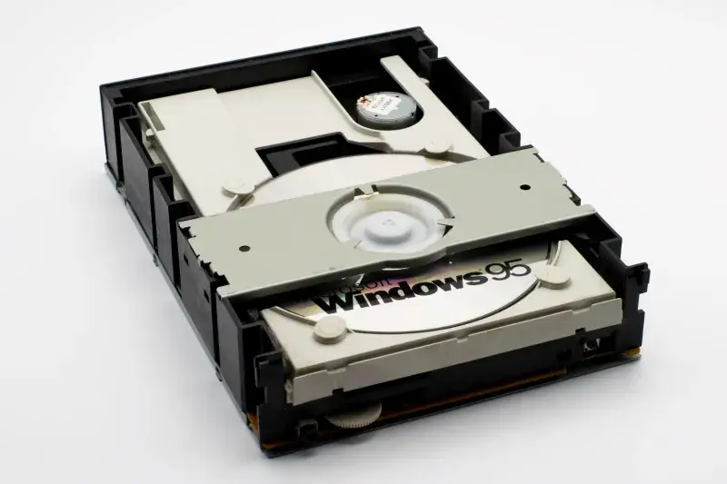 Close-up of a retro CD-ROM drive with a Windows 95 disc, showcasing vintage technology.