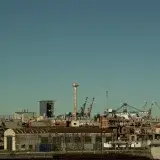View of an industrial area with tower cranes in Buenos Aires, Argentina, under a clear blue sky.