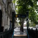 Escena urbana de la entrada de la estación de metro Perú en Buenos Aires con árboles bordeando la calle.