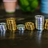 Pile of shiny gold and silver cryptocurrency coins on a wooden table.
