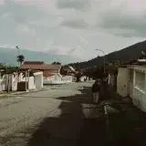 Quiet suburban street in Mérida, Venezuela, featuring tile-roofed houses and mountain views.