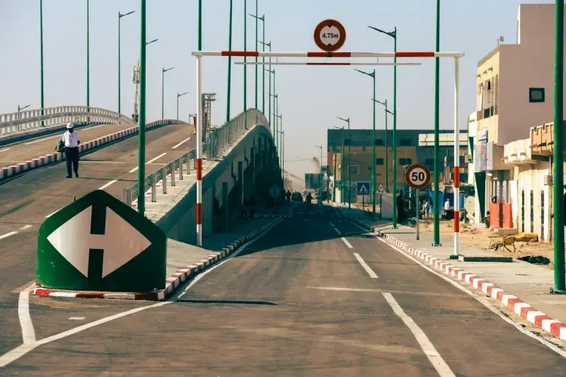 A cityscape featuring a modern bridge, clear road markings, and traffic signs, indicative of urban infrastructure.