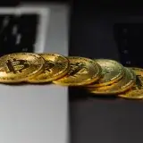 A stack of gold bitcoin coins placed on a laptop keyboard, symbolizing digital currency and finance.