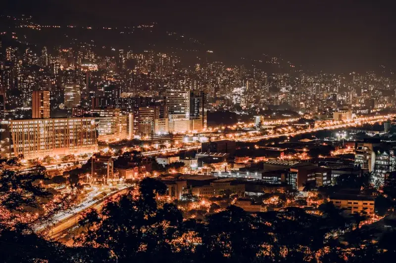 A vibrant night view of Medellin, Colombia with illuminated buildings and city lights.