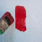 Close-up of a paintbrush applying red paint on a wall in Mérida, Venezuela.