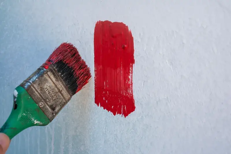 Close-up of a paintbrush applying red paint on a wall in Mérida, Venezuela.