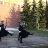 Ceremonial guards march outside the Kremlin walls in Moscow on a bright day.