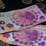 Close-up of colorful Argentine peso banknotes and coins on a dark backdrop.