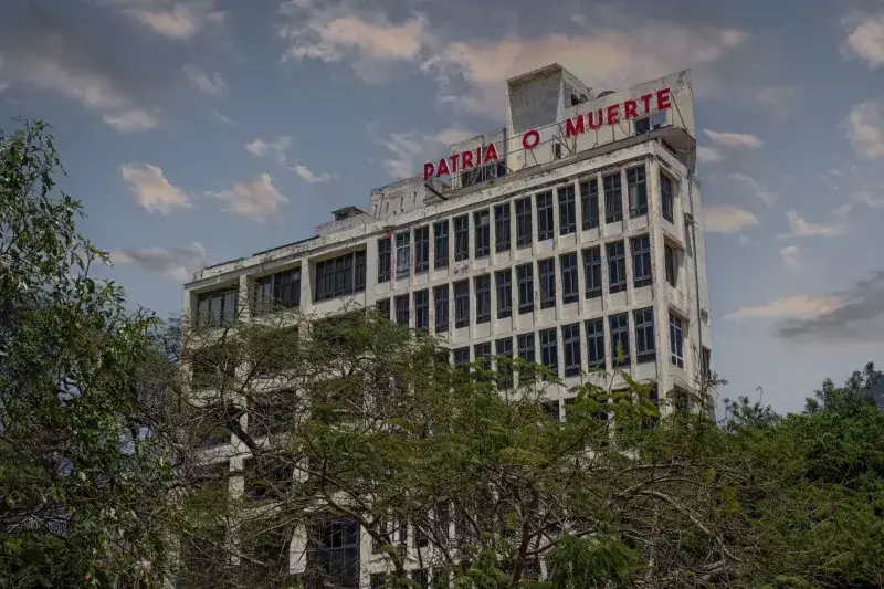 Historic building in Havana, Cuba with iconic Patria o Muerte sign against a blue sky.