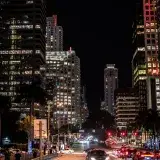 A lively nighttime scene in downtown Miami with illuminated skyscrapers and bustling traffic.