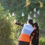 A humanitarian worker wearing a World Vision vest assists a child in a lush, sunny environment.