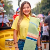 A cheerful woman in a yellow shirt at a colorful festival parade in Villanueva, Colombia.