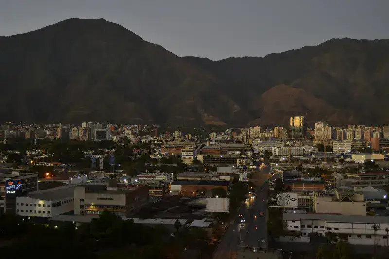 Una vista aérea de Caracas, Venezuela, que muestra el paisaje urbano con montañas al atardecer.