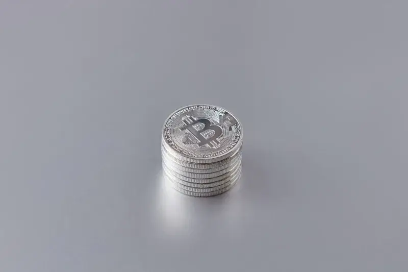 Close-up of silver Bitcoin coins stacked on a gray surface, showcasing cryptocurrency technology.