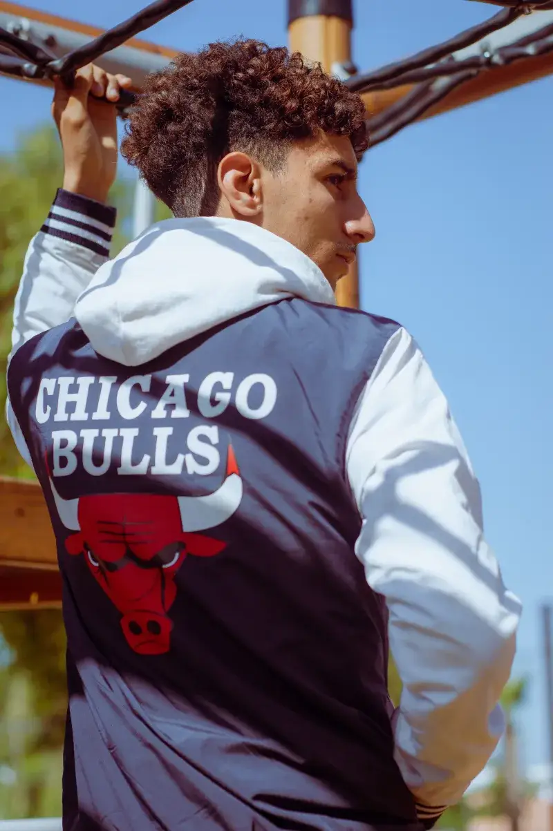 Young man wearing a Chicago Bulls jacket, gazing outdoors in Casablanca, Morocco.