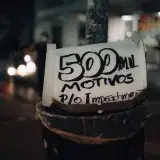 A street pole displaying a protest sign with the message '500 mil motivos p/o impeachment' at night.