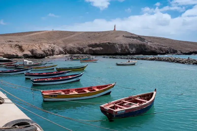 Lively scene of colorful fishing boats anchored in the serene waters of Pedra Lume, Sal, Cabo Verde.