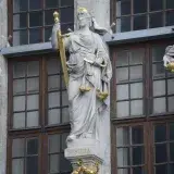Vista detallada de las estatuas de Justicia, Europa y Asia en la fachada de un edificio histórico que muestra justicia y continentes.