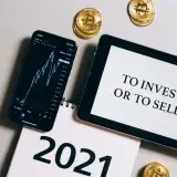 Overhead view of tablet, smartphone with chart, Bitcoin coins symbolizing investment choices for 2021.