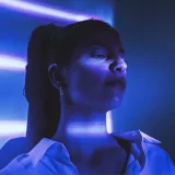 Young female sits under blue light