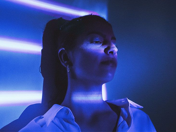 Young female sits under blue light