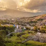 Aerial shot of Medellin, Colombia, showcasing urban sprawl and hills at sunset.