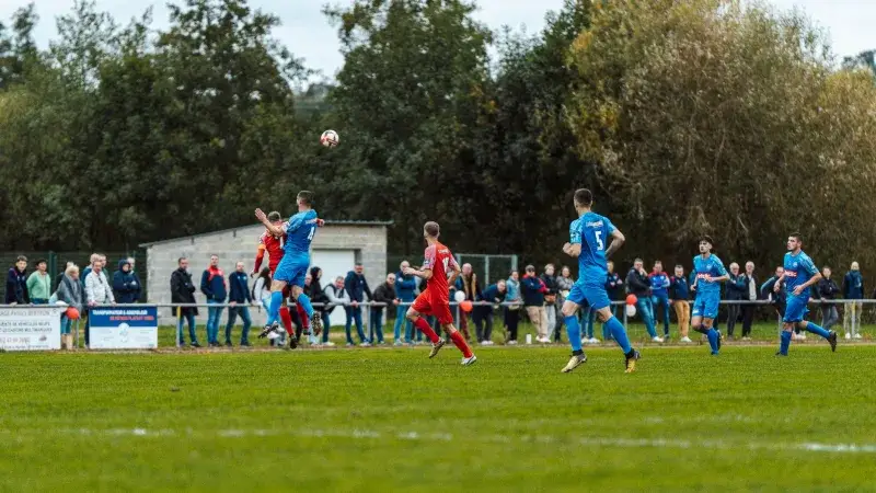 Players in blue and red compete intensely on a football field in France, capturing the spirit of the game.