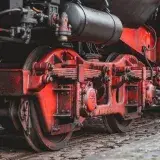 Detail shot of a vintage red steam locomotive showcasing its wheels and mechanical components.