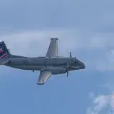 A military transport airplane flying high against a clear blue sky, showcasing aviation technology.