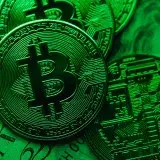 Close-up of Bitcoin coins on paper cash, with a green color tint.