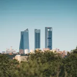 View of Madrid's Cuatro Torres Business Area surrounded by trees under a clear blue sky.